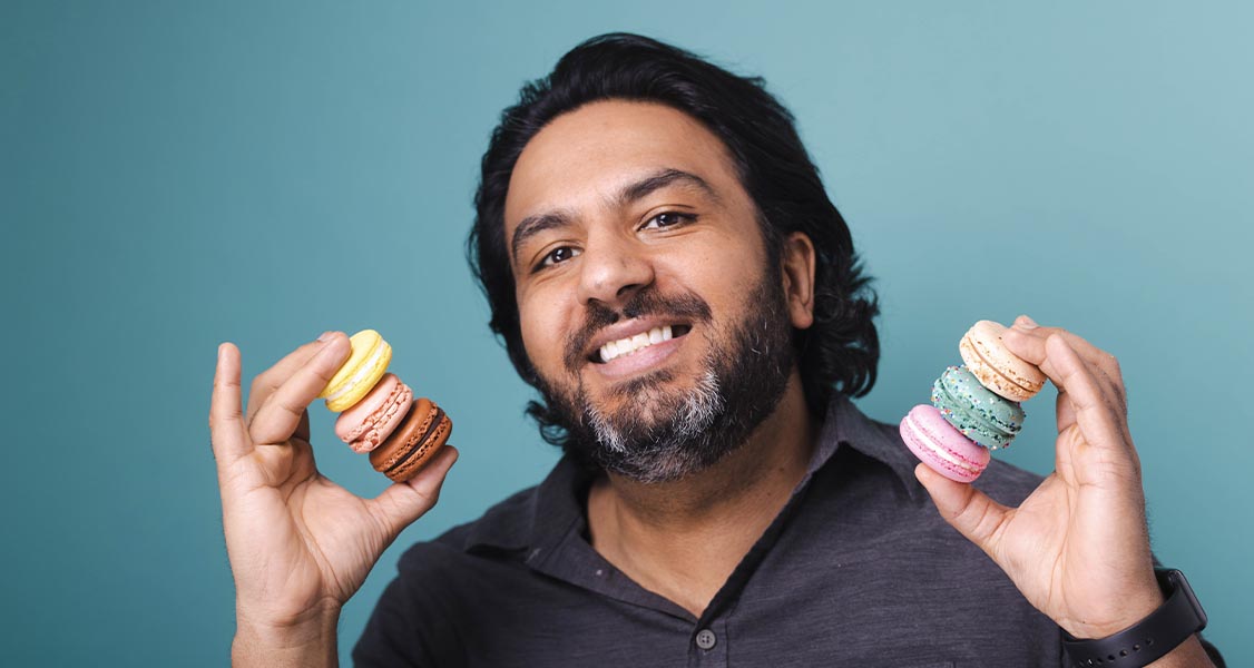 Man holds a stack of macarons in each hand.