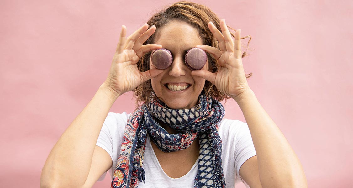 Woman playfully holds macarons in front of her eyes.