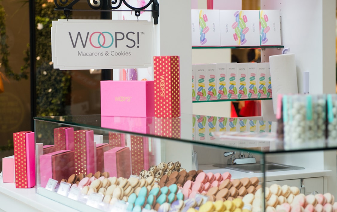 Woops! Macarons & Gifts kiosk full of assorted macarons and macaron boxes.