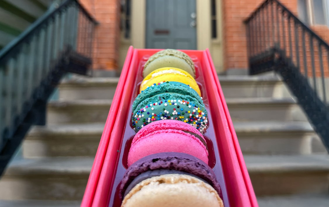 Box of five Woops! macarons in front of a door. 