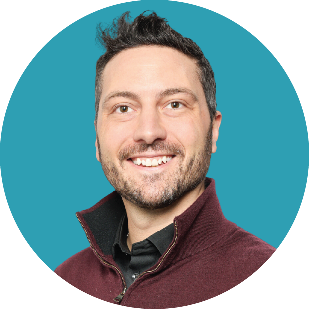 Man smiling with a teal background.